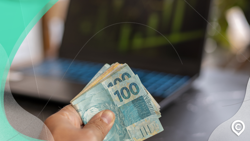 pessoa segurando maço de notas de 100 reais